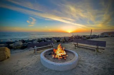 a fire pit on the beach with a sunset in the background at Villa Jules, Oceanfront, Private Beach, Fire Pit in Oceanside