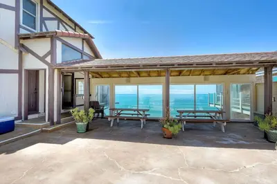 a patio with two picnic tables and a view of the ocean at Villa Jules, Oceanfront, Private Beach, Fire Pit in Oceanside