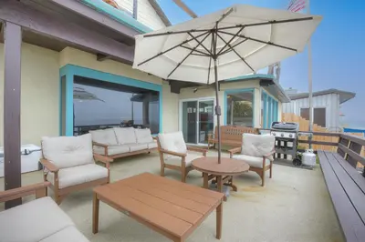 a patio with a table and chairs and an umbrella at Oceanfront 4BR, Private Beach & Patio, Remodeled Kitchen in Oceanside