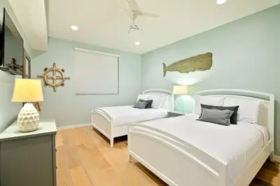 a bedroom with two beds and a table with a lamp at Stunning Oceanfront Getaway at Windansea Beach in San Diego