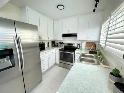 a kitchen with white cabinets and a stainless steel refrigerator at SurfView VR - Best Ocean and Pier View, 5 mins to Beach, Cozy Patio, Pet Friendly in San Clemente