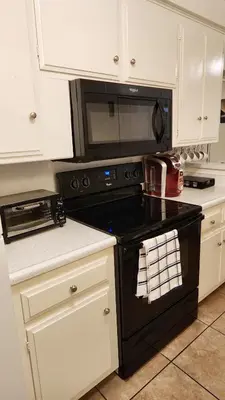 a kitchen with a black stove and a microwave at Centrally Located, 4x Queen, 300 MBPS Internet with Backyard! in Hemet