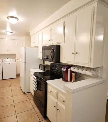 a kitchen with white cabinets and black appliances at Centrally Located, 4x Queen, 300 MBPS Internet with Backyard! in Hemet