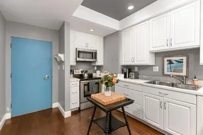 a kitchen with white cabinets and a table with flowers on it at 689 - Steps to the Resort, Peaceful Studio with free Wifi & Parking in Encinitas