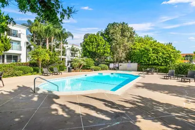 a swimming pool with chairs and a building at 604 Gorgeous Renovated Condo, Steps to Omni Spa, Golf, Tennis, PFC & Exclusive Building Pool in Encinitas