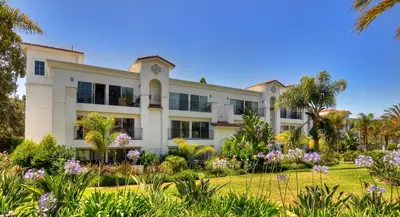 a large white building with palm trees and flowers at 647 Luxury Inside The Gates LaCosta Resort-Top Floor Steps from Resort 647 in Encinitas