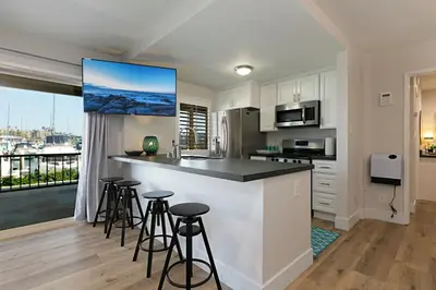 a kitchen with white cabinets and a counter with bar stools at 106B New Renovation! Huge Patio with Harbor View in Oceanside
