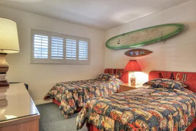 a hotel room with two beds and a surfboard on the wall at 210A Marina Del Mar - Beach View in Oceanside