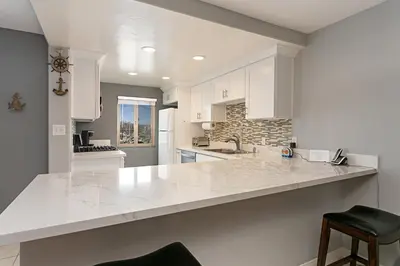 a kitchen with white cabinets and a white counter top at 210B Harbor Views Short Stroll to Beach, Large Balcony, Walk to Dining Shops in Oceanside