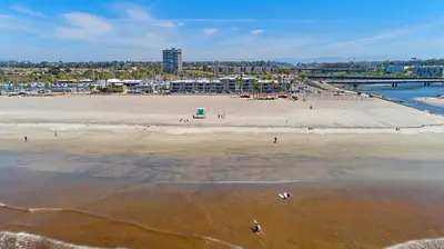 an aerial view of a beach with people in the water at 210B Harbor Views Short Stroll to Beach, Large Balcony, Walk to Dining Shops in Oceanside