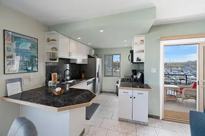 a kitchen with white cabinets and a view of the city at 301B Ocean Harbor View - Top Floor Corner Unit in Oceanside