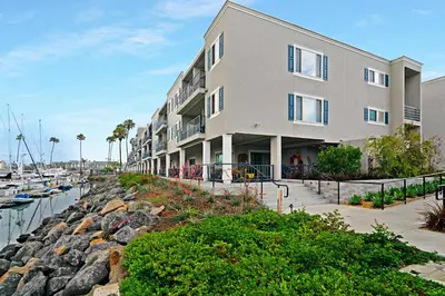 a large apartment building next to a marina at 301B Ocean Harbor View - Top Floor Corner Unit in Oceanside