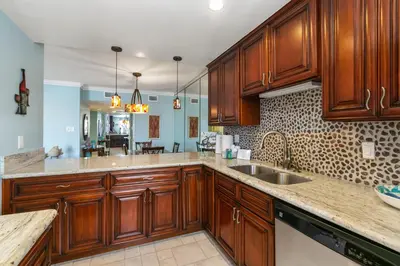 a kitchen with wooden cabinets and a sink at 305B - Seaside at the Marina - 100 Steps to the Sand in Oceanside