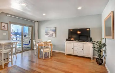 a kitchen and dining room with a table and a television at 307B Steps from the sand! Freshly Decorated with Harbor Views in Oceanside