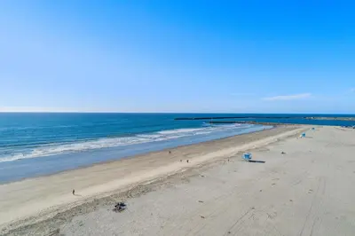 an empty beach with the ocean on a sunny day at 307B Steps from the sand! Freshly Decorated with Harbor Views in Oceanside