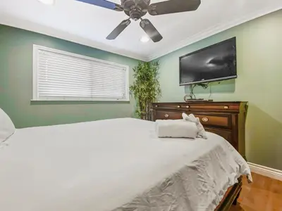 a bedroom with a bed and a flat screen tv at 311B Harbor Views and Steps to the Sand in Oceanside