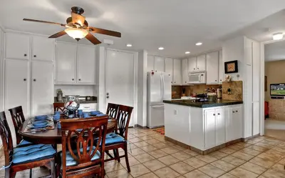 a kitchen and dining room with a table and a ceiling fan at Tropical Water View at North Coast Village C200 in Oceanside