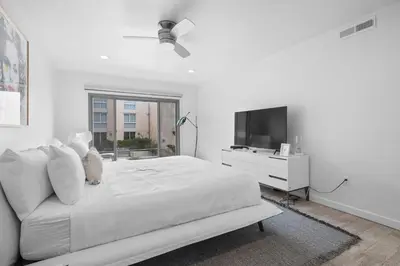 a white bedroom with a white bed and a tv at Beachfront Oasis - 30-Night Minimum in San Diego