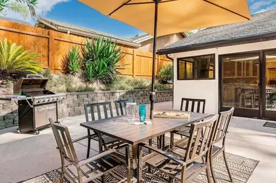 a wooden table with chairs and an umbrella on a patio at Poppy Cottage in Carlsbad