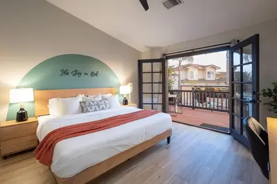 a bedroom with a large bed and a balcony at Entire house - 4 Bedroom & 2 Bath, 5 Min to Beach in Oceanside