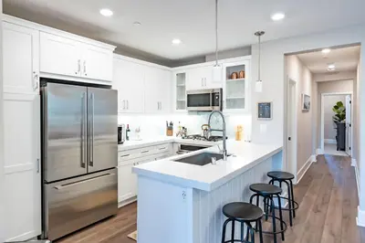 a kitchen with white cabinets and a stainless steel refrigerator at Pristine and Luxe, Steps to Mission Beach and Bay! in San Diego