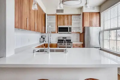 a kitchen with a white counter top and wooden cabinets at Little Italy studio w gym pool nr light rail SAN-6 in San Diego