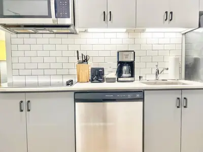 a kitchen with white cabinets and a dishwasher at Cozy Couple's Corner in Downtown San Diego in San Diego