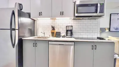 a kitchen with white cabinets and a stainless steel refrigerator at Boutique Suite in Downtown San Diego in San Diego