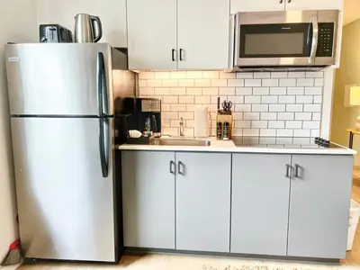 a kitchen with white cabinets and a stainless steel refrigerator at Grand Downtown San Diego Apartment in San Diego