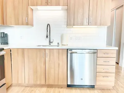 a kitchen with wooden cabinets and a stainless steel dishwasher at Skyline Flat Facing Downtown San Diego in San Diego