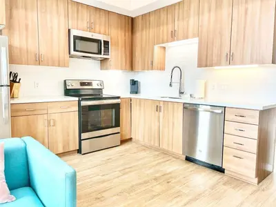 a kitchen with stainless steel appliances and wooden cabinets at Skyline Flat Facing Downtown San Diego in San Diego