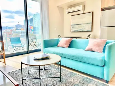 a living room with a blue couch and a table at Skyline Flat Facing Downtown San Diego in San Diego