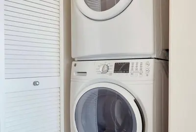 a white washing machine next to a window at City View Apartment in Downtown! in San Diego