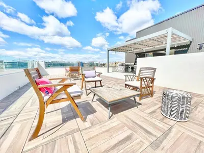 a patio with chairs and tables on a roof at City View Apartment in Downtown! in San Diego
