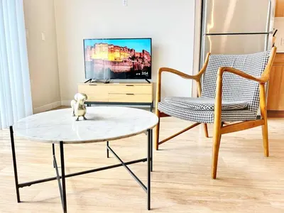 a living room with a table and a chair and a tv at The Executive Getaway in San Diego