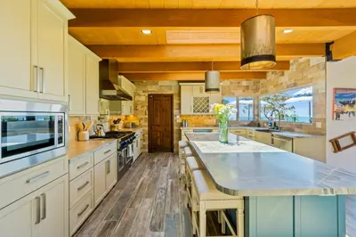a large kitchen with wooden ceilings and a large island at Casa Real | House in La Jolla in San Diego
