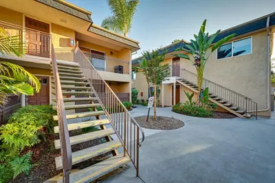 a staircase leading to a building with palm trees at Quiet San Diego Condo with Balcony, Pool and Hot Tub! in San Diego