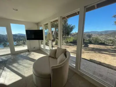 a living room with a chair and a tv and windows at The most breathtaking Lake and Mountain View in Fallbrook