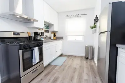 a kitchen with white cabinets and a black stove at Nautical Point Loma Getaway - 7 mins to airport in San Diego