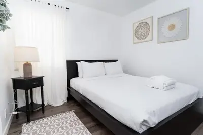 a white bedroom with a large bed and a night stand at Nautical Point Loma Getaway - 7 mins to airport in San Diego