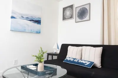 a living room with a black couch and a glass table at Seaside Point Loma Home with Outdoor Patio in San Diego