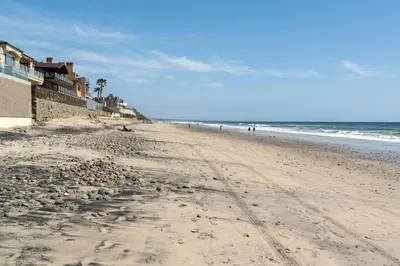 a sandy beach with people walking on the ocean at CB-2445A - Carlsbad Casa De Los Sueños | Unit A in Carlsbad