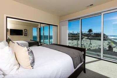 two beds in a bedroom with a view of the ocean at Unbeatable Location - Steps to Moonlight Beach in Encinitas