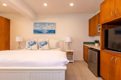 a bedroom with a white bed and a flat screen tv at Unbeatable Location - Steps to Moonlight Beach in Encinitas