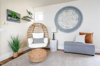 a room with a rattan chair and a ottoman at Stunning Oceanfront Home - Incredible Views in Oceanside