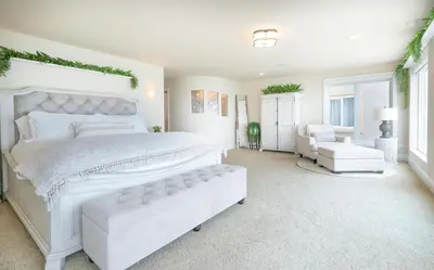 a white bedroom with a large white bed and a chair at Stunning Oceanfront Home - Incredible Views in Oceanside