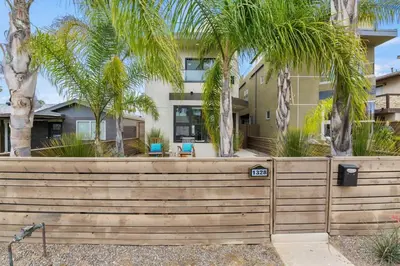 a fence with palm trees in front of a building at Pacific Beach Paradise by Cardo -Spacious Retreat in San Diego