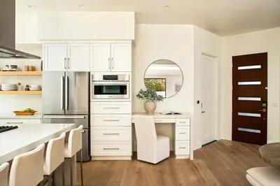 a kitchen with white cabinets and a table with a mirror at Contemporary Indoor Outdoor Living Walk to Beach in Encinitas