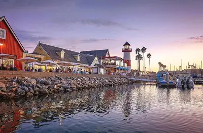 a harbor with a lighthouse and a marina with people at Mile to Beach! Private, Family & Pet Friendly Oasis! Pool Table & Hot tub! in Oceanside