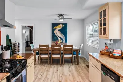 a kitchen with a dining room table with a bird painting on the wall at Mile to Beach! Private, Family & Pet Friendly Oasis! Pool Table & Hot tub! in Oceanside